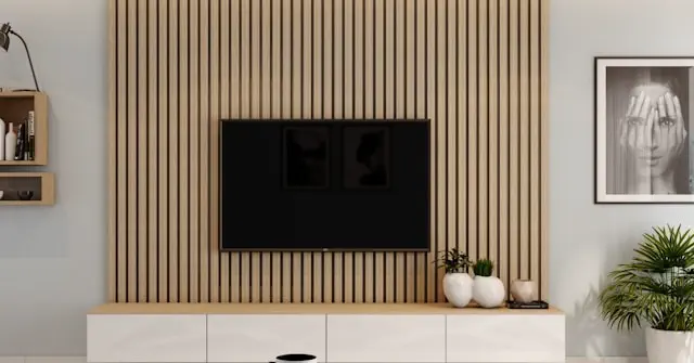 Custom TV and media unit service in the Dubai featuring a modern wall mounted TV panel with vertical wooden slats, built in storage cabinets, and minimalist interior design setup