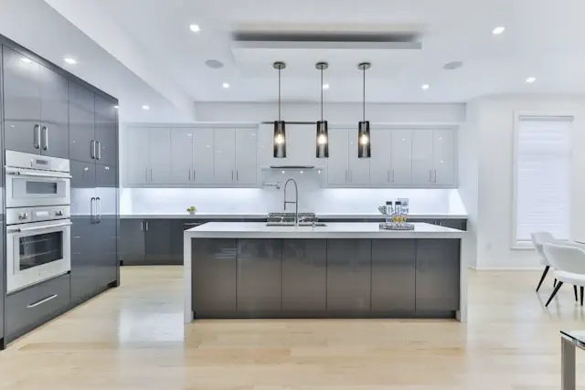 Kitchen renovation service in the Dubai featuring a modern kitchen with sleek grey cabinets, central island, built in appliances, and contemporary lighting design