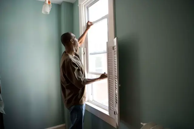 Window installation service in the Dubai showing a professional installing a modern window frame with shutters, ensuring proper fitting and interior finishing in a residential space